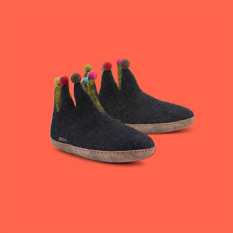 Betterfelt Jester Slipper in Black Wool Felt With Leather Soles Against a Coral Colored Backdrop